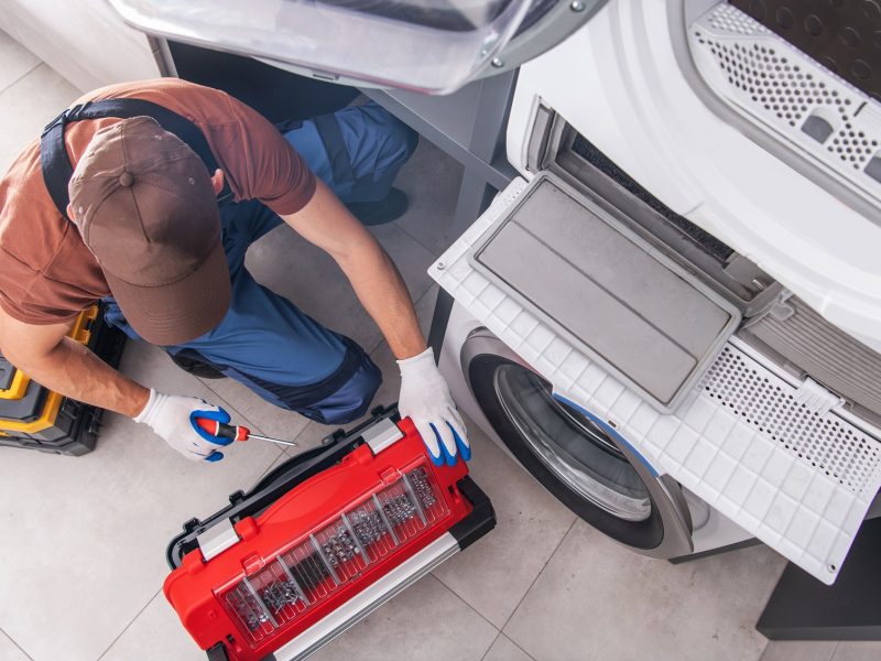 Residential Washing Machine Fixing by Caucasian Professional Technician. Home Appliances Issues Theme.